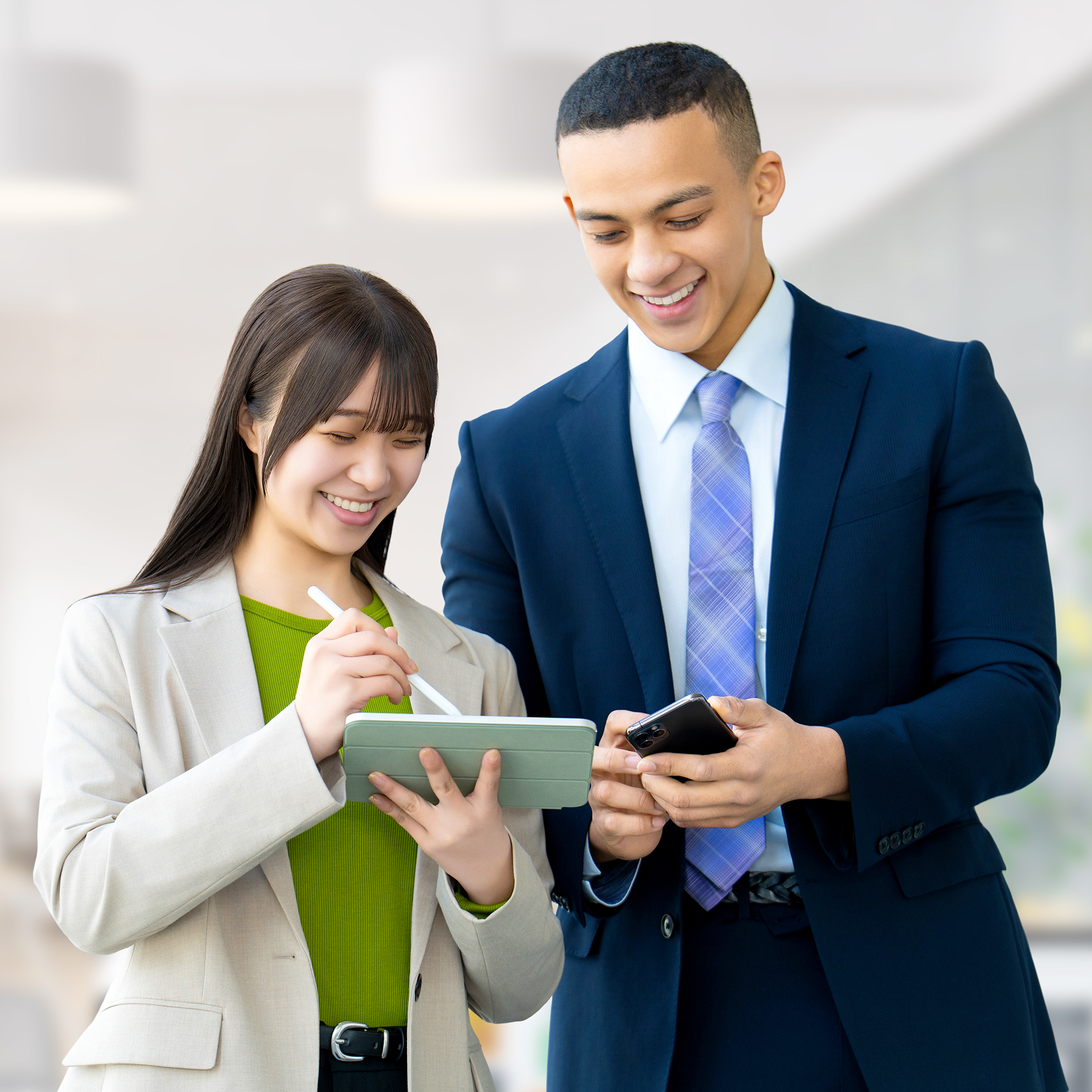 外国人男性と日本人女性がタブレット端末を見ながら笑顔で会話する様子