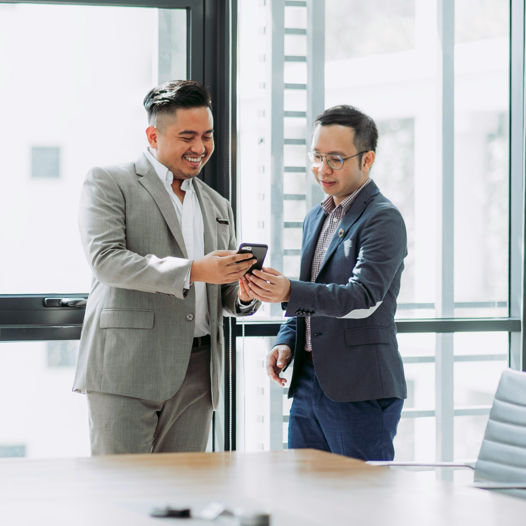 外国人男性と日本人男性がスマートフォンを見ながら笑顔で会話する様子